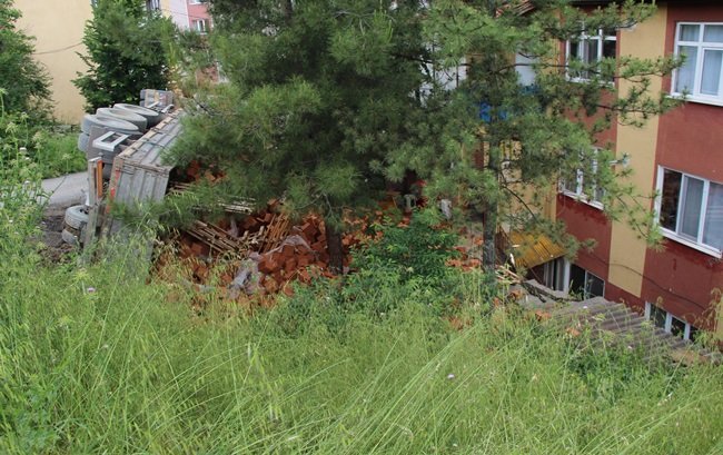 TUĞLA YÜKLÜ TIR, 1009 NOLU CADDE ÜZERİNDEN DÖNÜŞ YAPTIĞI SIRADA YOLUN SAĞ TARAFINDA BULUNAN 3 KATLI BİR BİNANIN BAHÇESİNE DEVRİLDİ. (YASİN ERDEM/KARABÜK-İHA)